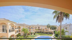 Un hotel con numerosi balconi, una piscina e un cortile con palme.