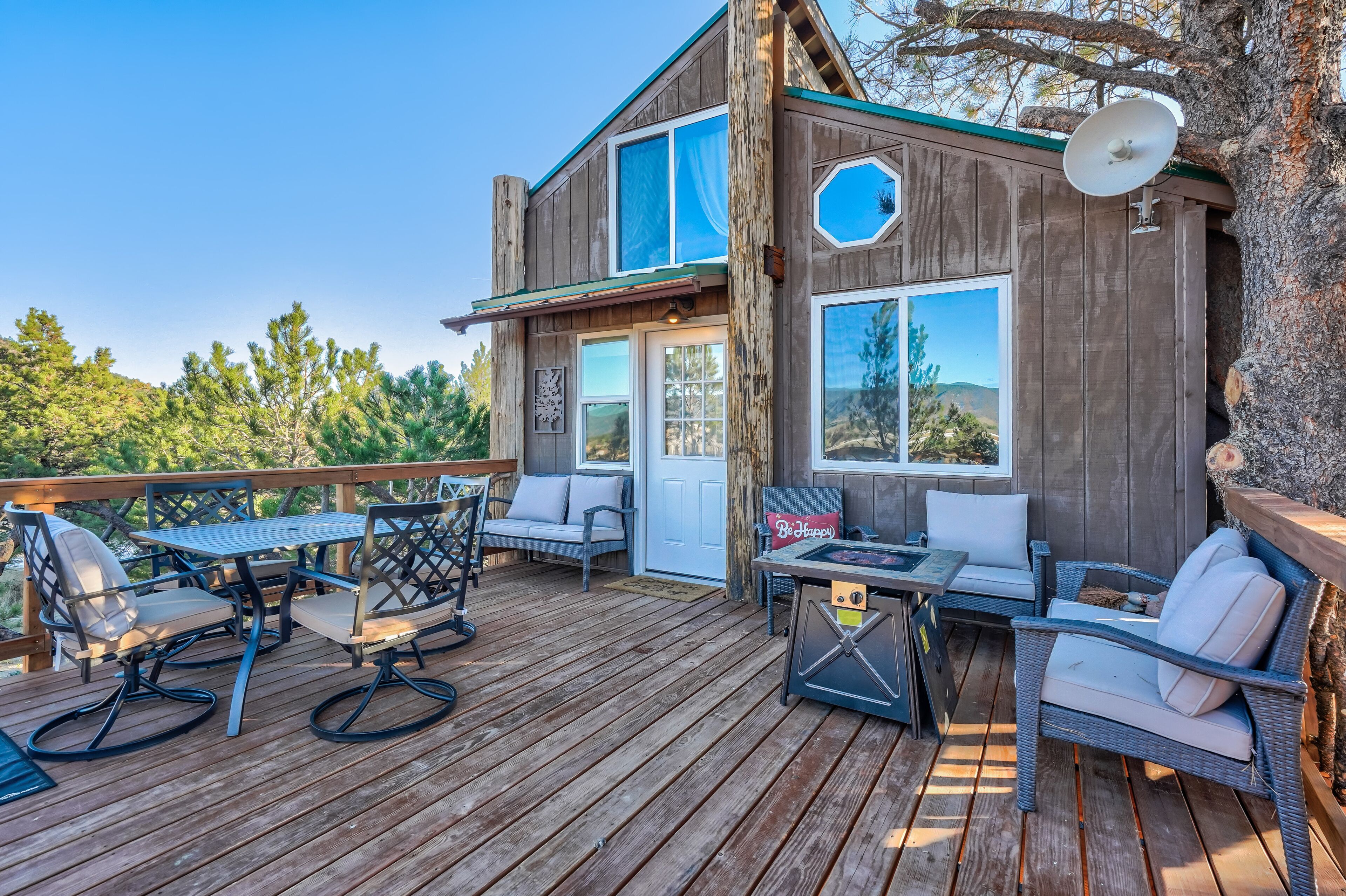 A wooden deck with outdoor furniture, a satellite dish, and a view of the surrounding landscape.