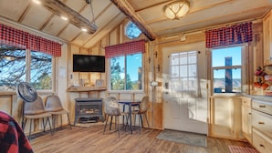 Un intérieur de chalet chaleureux avec une cheminée, un plancher en bois et un téléviseur.