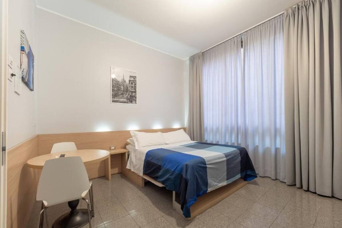 A hotel room with a bed, a desk, and a chair.
