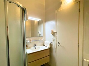 A bathroom with a sink, mirror, and a hairdryer mounted on the wall. - Navigli Suites (Milan)