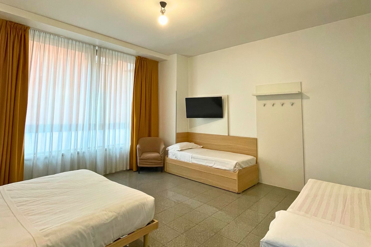 A hotel room with two beds, a TV mounted on the wall, and a chair.