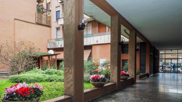 A corridor with a marble floor, large windows, and potted plants. - Navigli Suites (Milan)