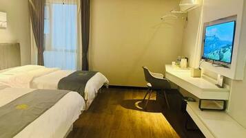 A hotel room with two beds, a desk with a chair, a television, and a window with curtains.