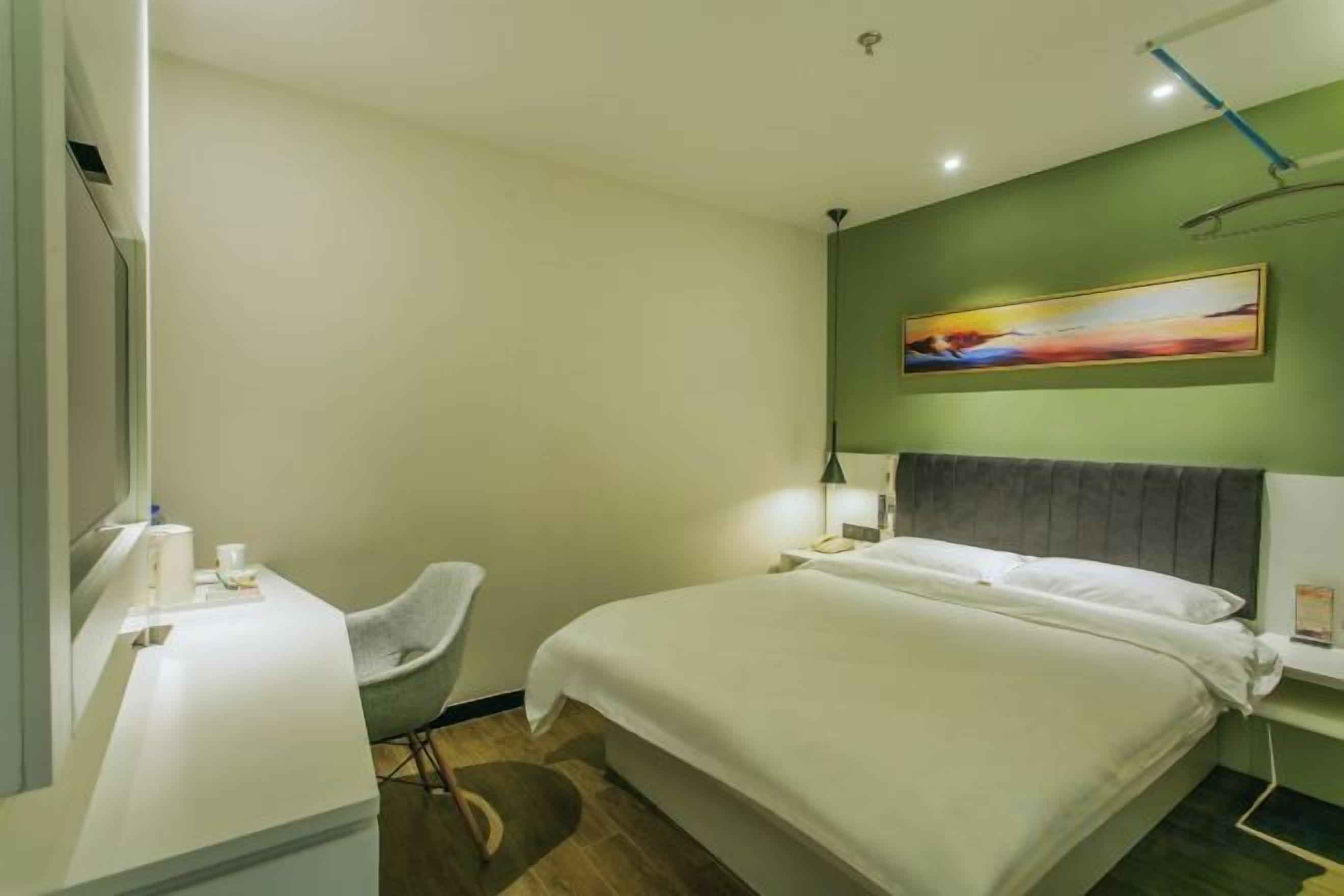 Une chambre d’hôtel avec un lit, un bureau, une chaise et un tableau au mur.
