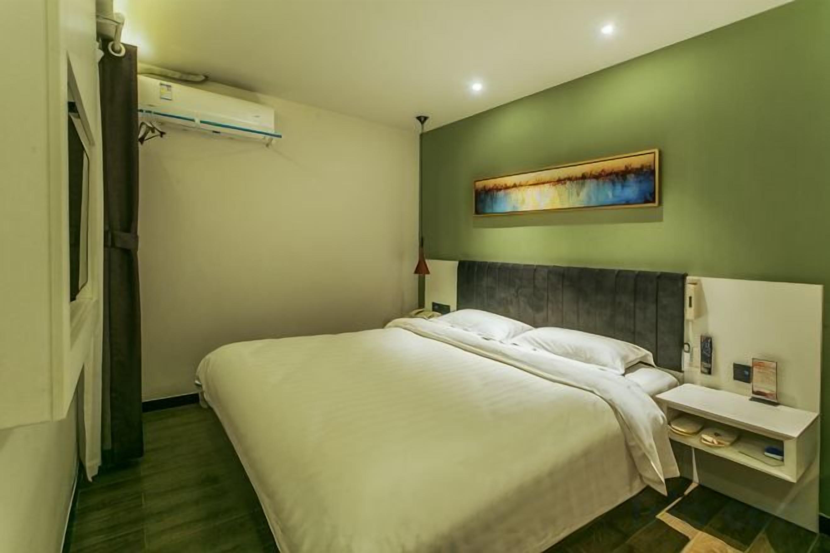 Una camera d'albergo con un letto, un comodino e un quadro appeso al muro.