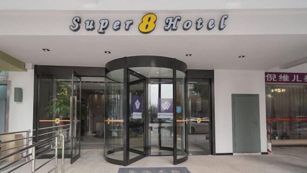 Super8-hotellin sisäänkäynti, jossa on pyörivät ovet ja tervetulomatossa.