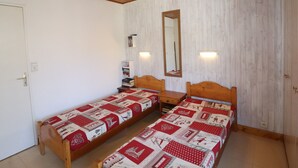 A room with two wooden beds, a mirror, and a small table.