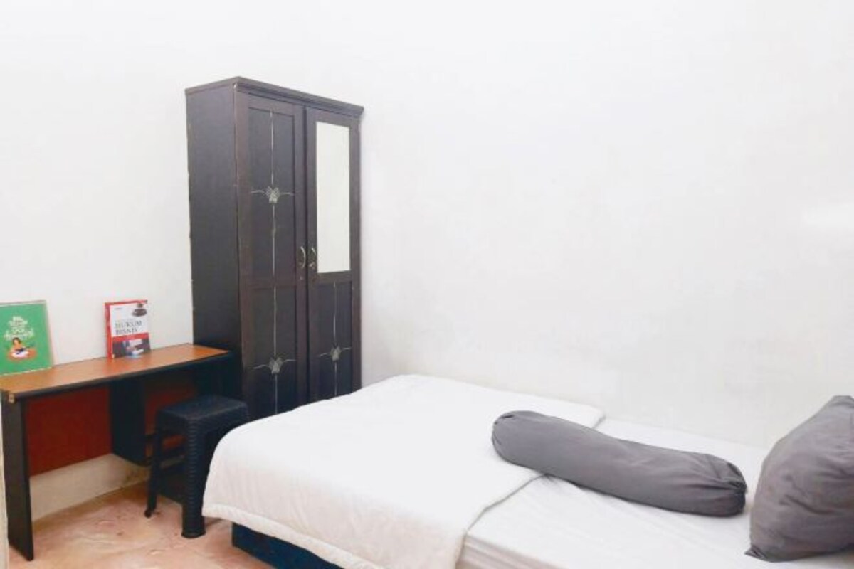 Une petite pièce simple, avec un lit, un bureau et une armoire.