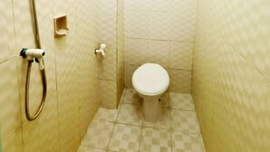 Een kleine badkamer met tegels, een douche, toilet en een klein plankje.