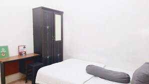 Een kleine slaapkamer met een bed, bureau en kledingkast.