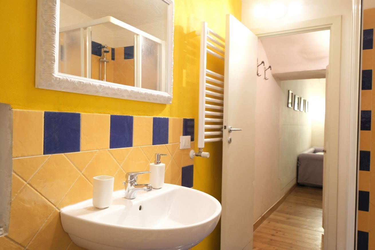 A bathroom with a white sink, mirror, and yellow and blue tiled walls.