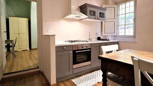 A compact kitchen with grey cabinets, a built-in oven, and a window providing natural light. - Wine Apartments Florence Nebbiolo (Firenze)