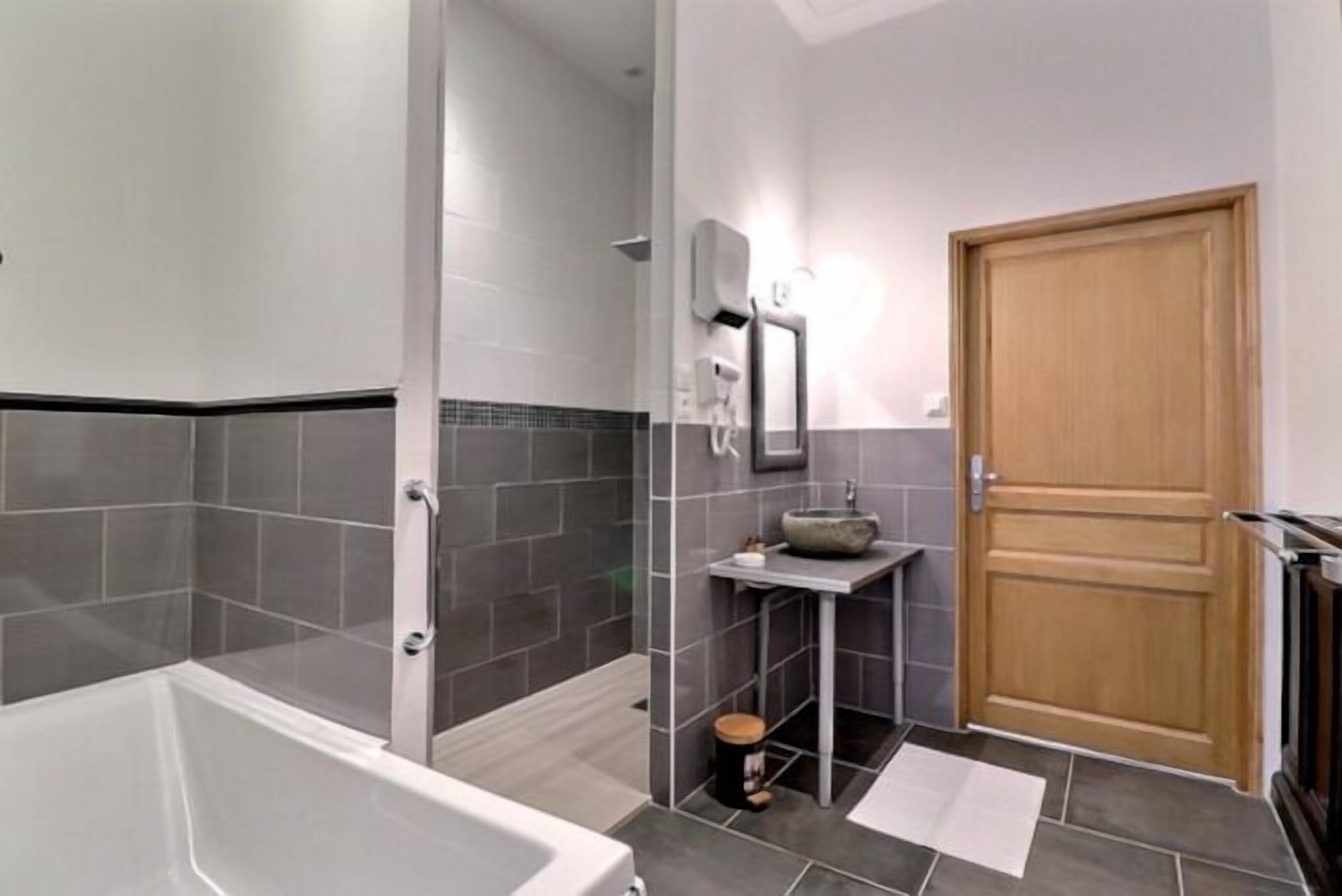 A modern bathroom with a glass-enclosed shower, a freestanding bathtub, and a small sink with a vessel basin.