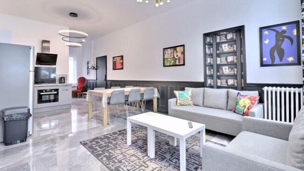 A modern living room with a sofa, a coffee table, and a dining area with chairs. - Les Appartements Fénelon (Le Cateau-Cambresis)
