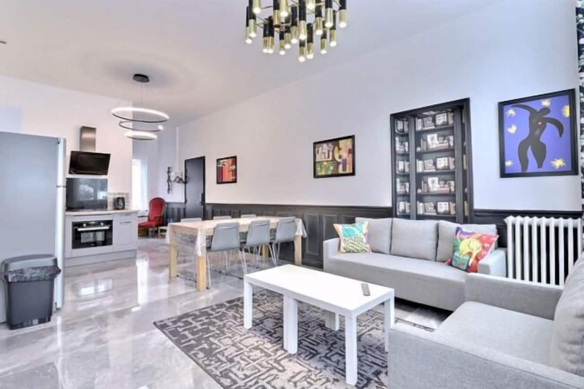 A modern living room with a sofa, a coffee table, and a dining area with chairs.