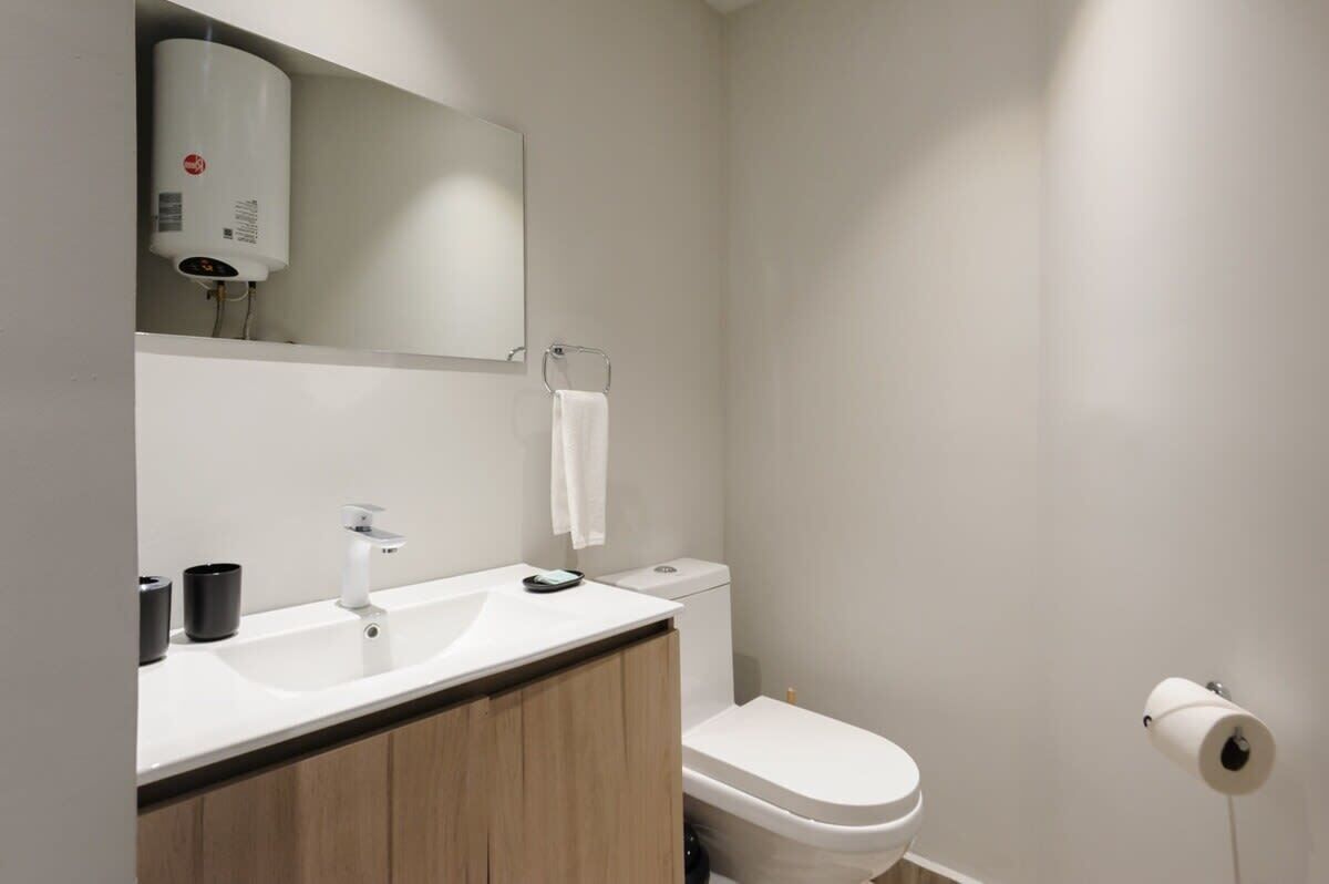 Une salle de bain moderne avec un lavabo blanc, un miroir et des toilettes.