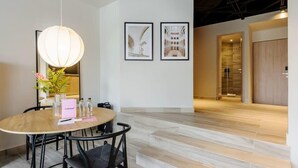 Uma sala de conferências moderna com uma mesa redonda, cadeiras, um lustre pendurado, quadros nas paredes e uma escadaria para outra área.