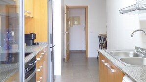 Een moderne keuken met granieten aanrechtbladen, roestvrijstalen apparatuur en houten keukenkastjes.