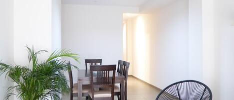 Un comedor con una mesa, sillas, una planta en maceta y una silla negra.