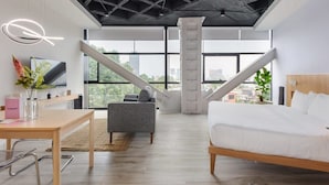 A modern hotel room with a large bed, a desk, a chair, and a staircase leading to an outdoor terrace. - w* | Comfy Loft near Polanco (Ciudad de México)