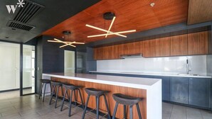 A modern kitchen with a central island, bar stools, and wooden cabinetry. - w* | Captivating 1BR in San Isidro (San Isidro)