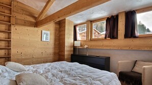 Een gezellige houten kamer met een bed, een bureau en een stoel.