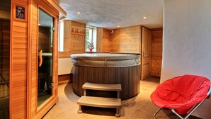 Een kamer met een whirlpool, houten wanden, een glazen deur en een rode stoel.