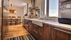 Een moderne keuken met houten kastjes, een groot raam en uitzicht op de omgeving.