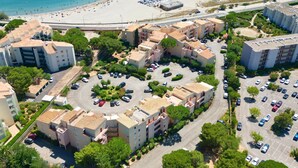 Vue aérienne d’un quartier résidentiel situé sur la côte, avec des immeubles d’appartements, un parking et une plage.