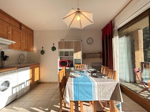 Una cocina compacta con armarios de madera, microondas integrado y comedor con mesa dispuesta para cuatro.