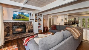 A modern living room with a stone fireplace, a grey sofa, and a television mounted above the fireplace.