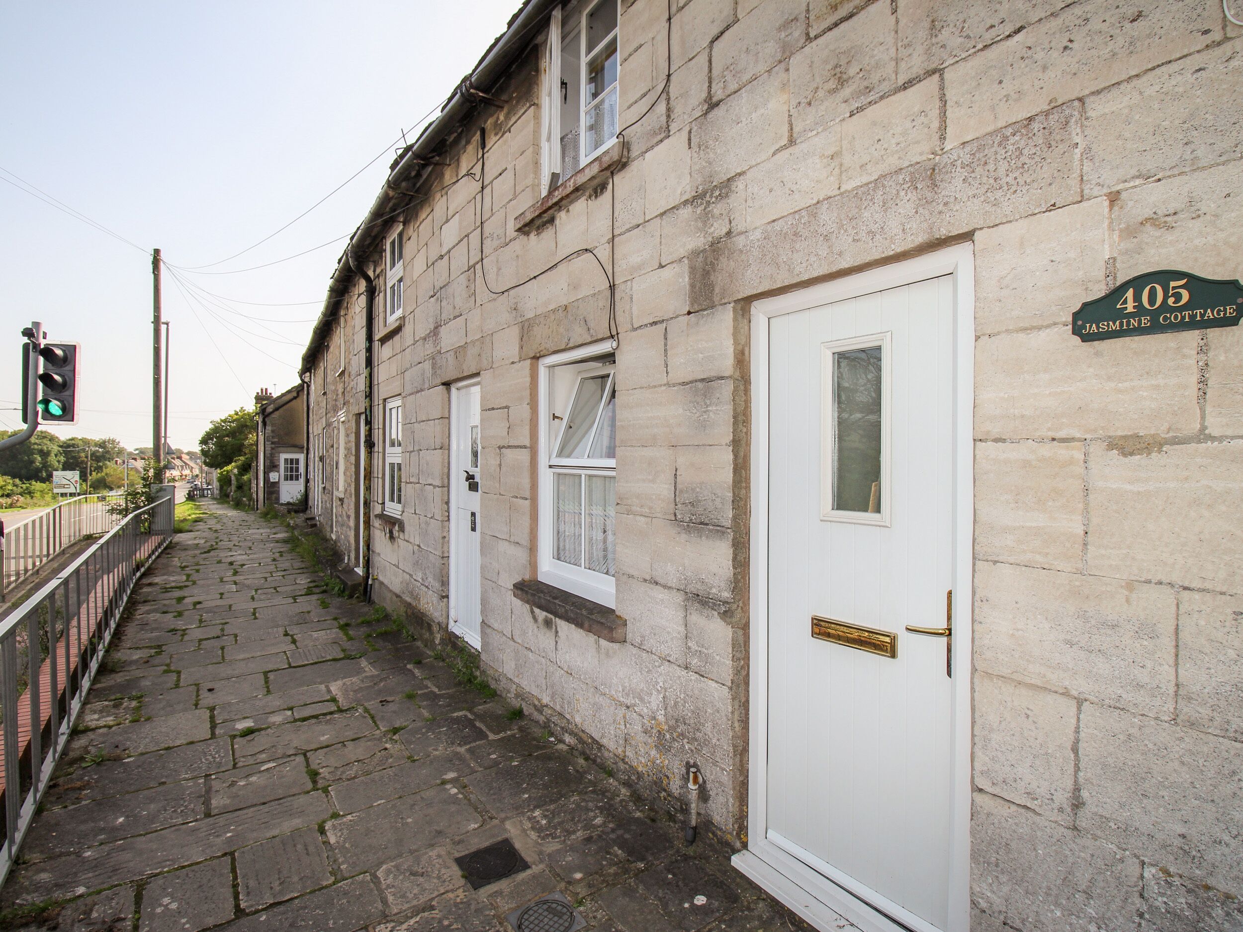 A stone building with a white door and a sign reading "405 Jasmine Cottage."