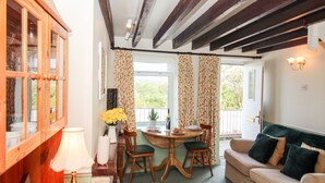 A cozy room with a dining table, chairs, a sofa, and a cabinet. - Jasmine Cottage (Swanage)