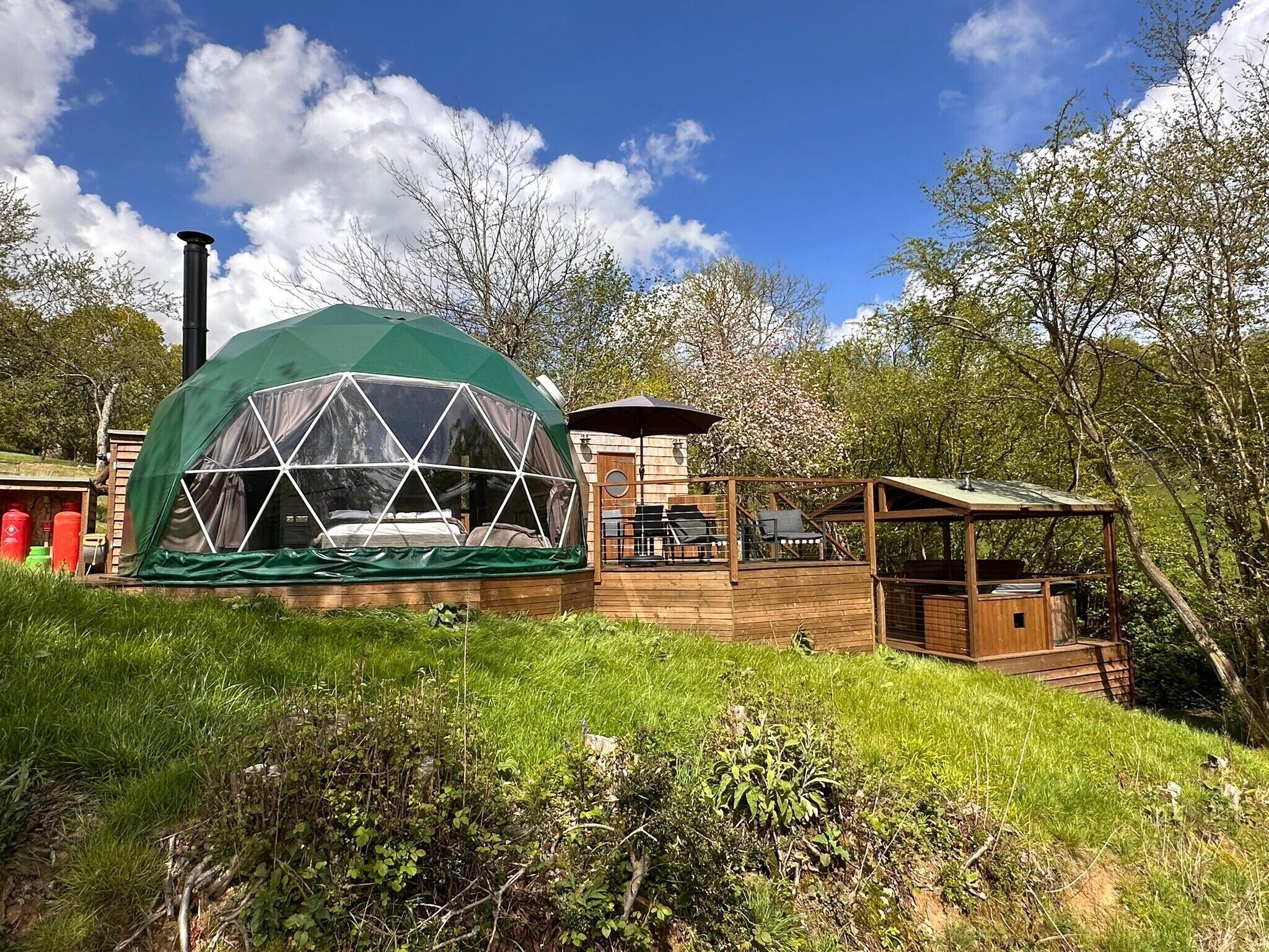 A geodesic dome structure with a wooden deck and a small attached building.