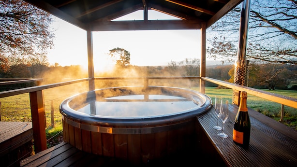 A hot tub with a wooden deck and a bottle of champagne. - Luna Domes (Edenbridge)
