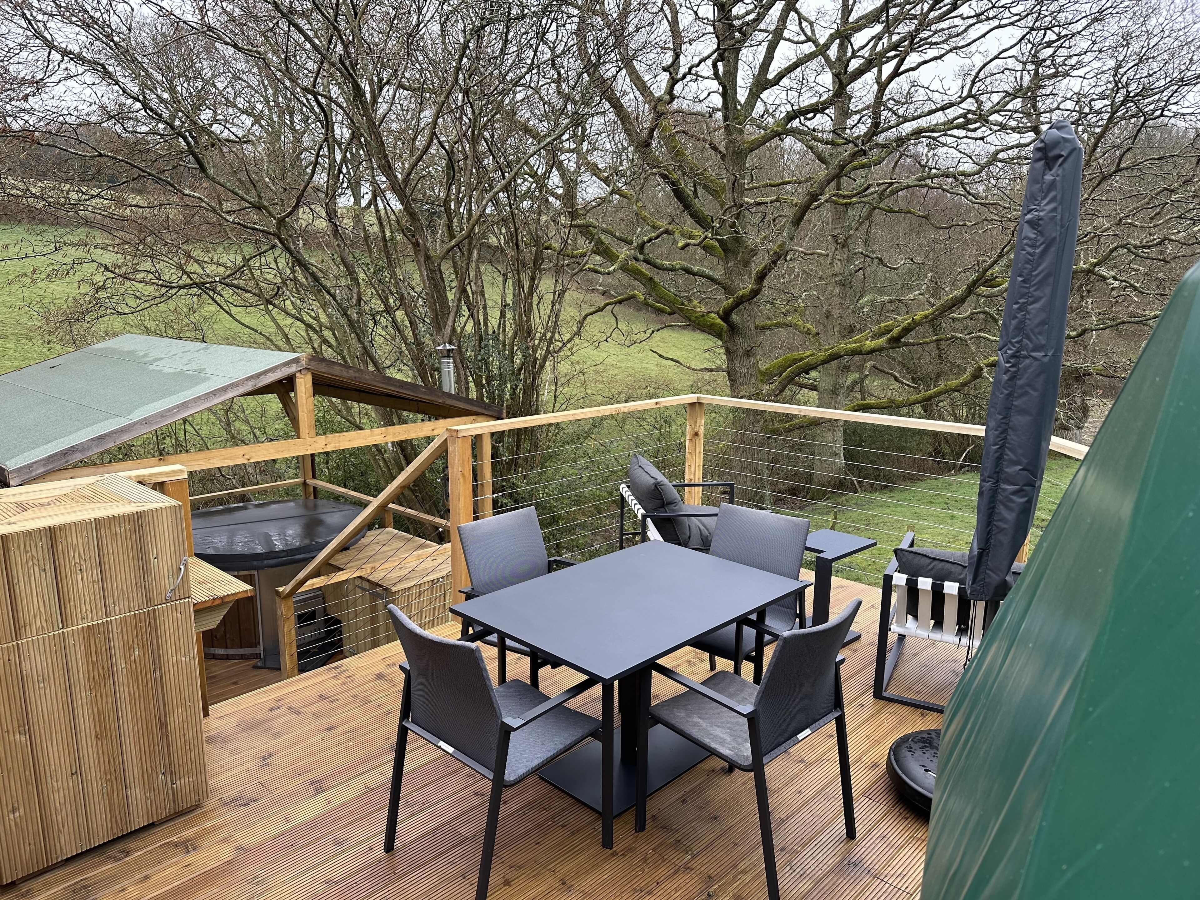 A wooden deck with a table and chairs, surrounded by trees.