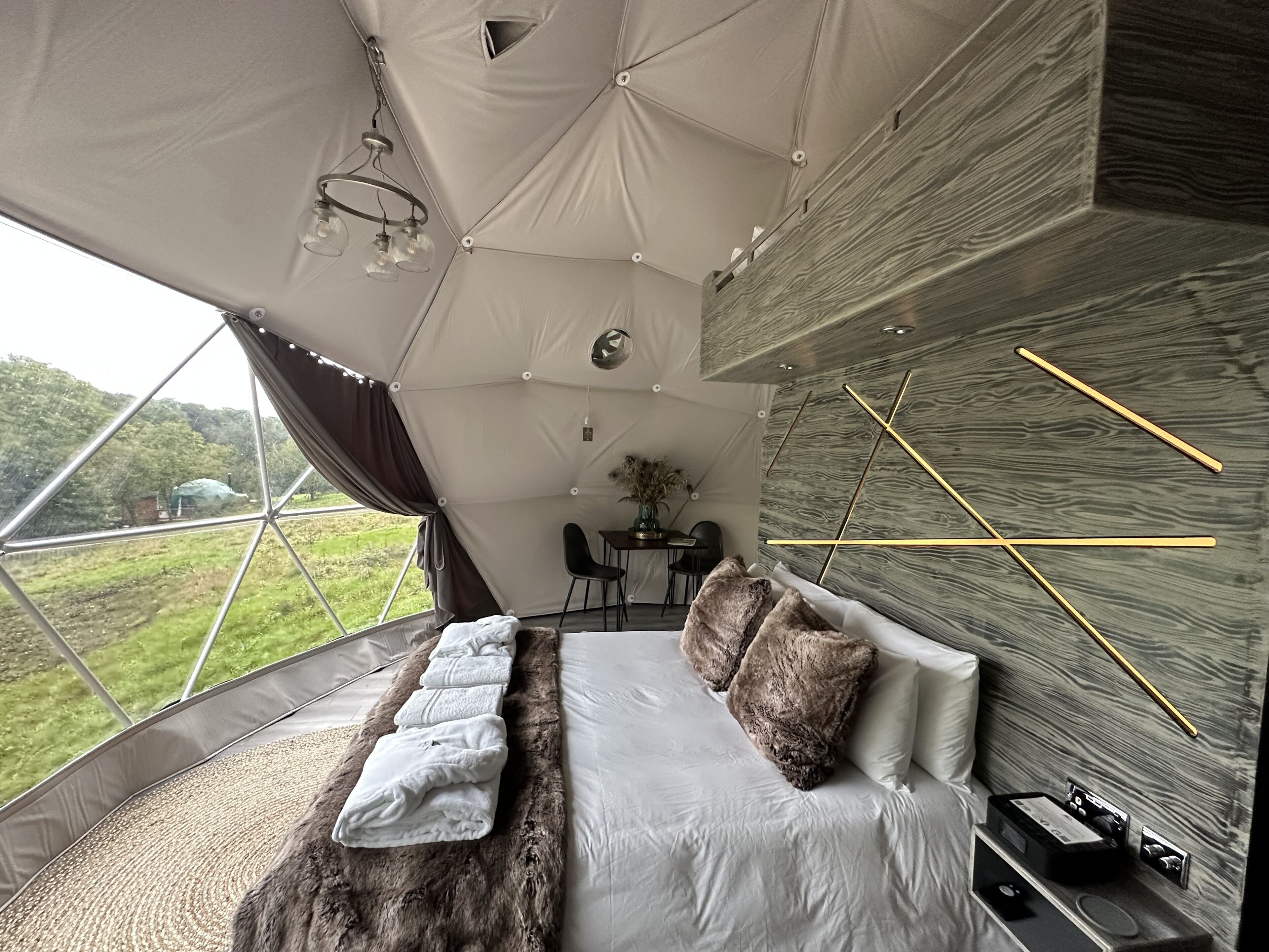 Un alojamiento moderno tipo tienda con una cama, un comedor y vistas al exterior.