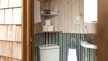 A wooden-paneled bathroom with a toilet, a sink, and a mirror.