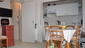 A compact living space with a dining area, kitchenette, and a television on a dresser.
