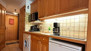 A kitchen with wooden cabinets, a Bosch dishwasher, a washing machine, and a coffee maker. - Charming apartment in Morillon, near cable car (Morillon Village)