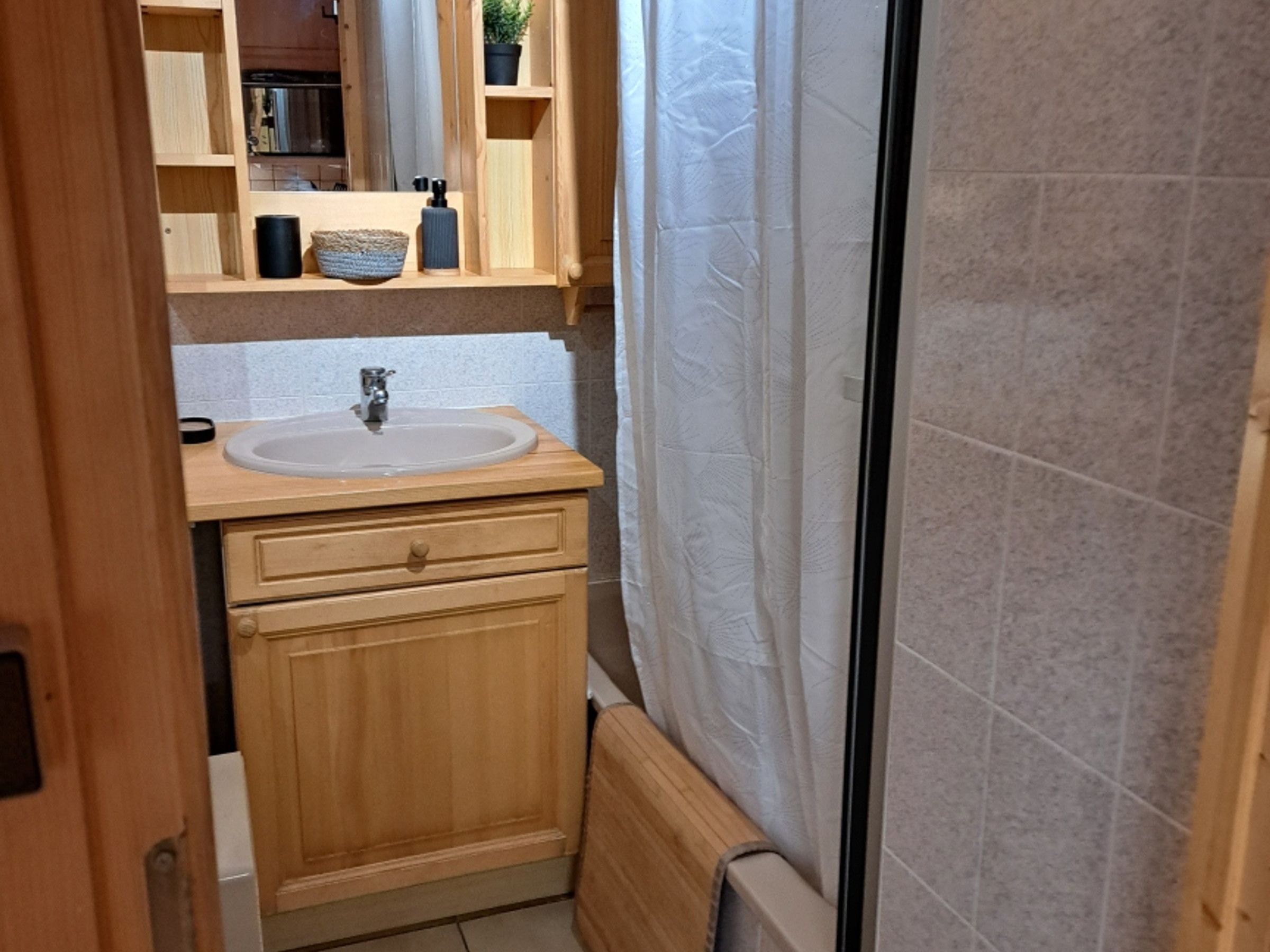 A bathroom with a wooden vanity, a sink, and a shower curtain.