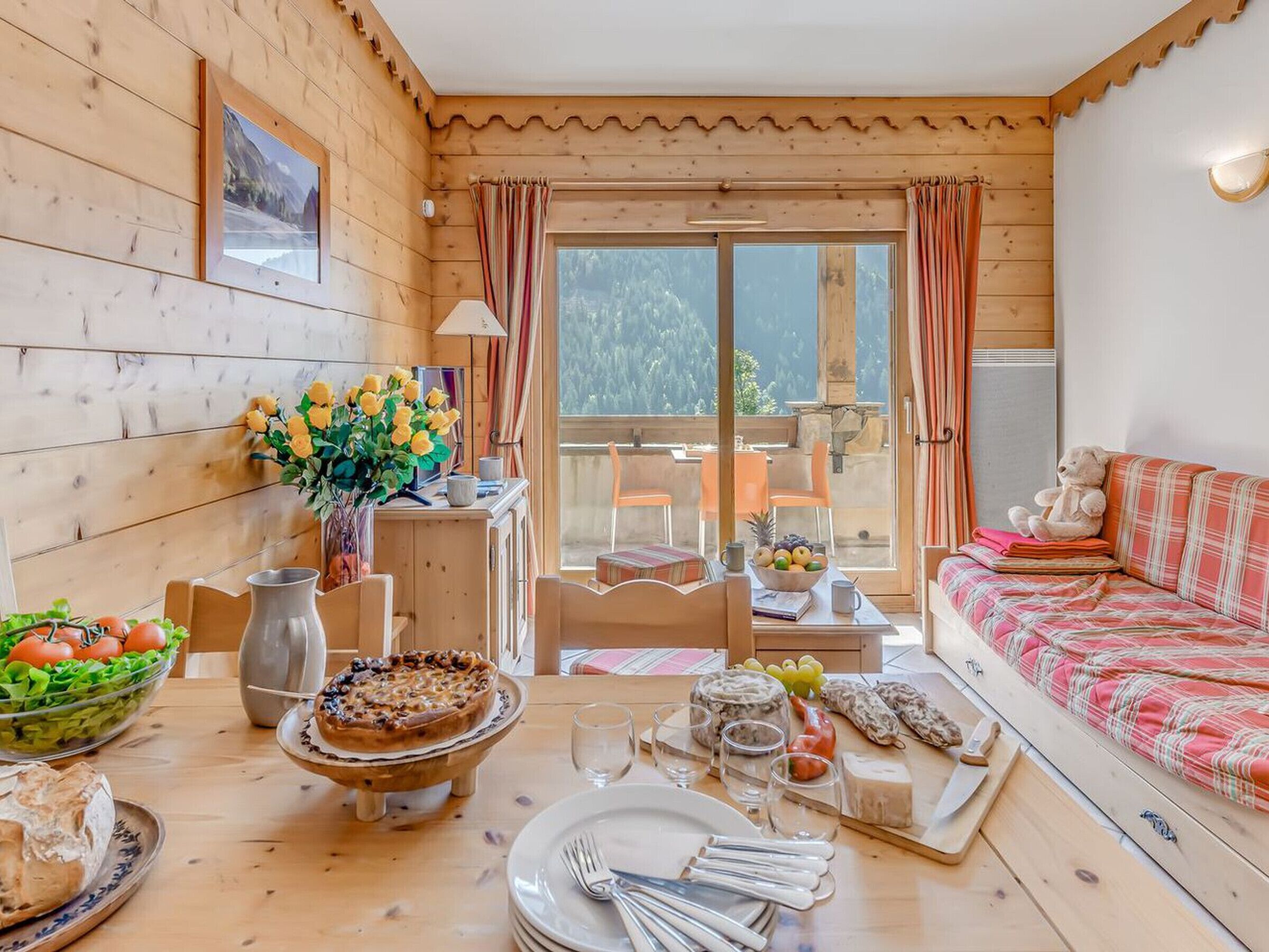 A cozy wooden cabin with a dining area, a sofa, and a view of the outdoors.
