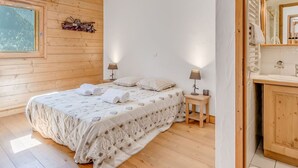 Makuuhuoneessa on puulattia, kuviollinen päiväpeite päällystetty sänky, kaksi yöpöytävalaisinta ja ikkuna, josta avautuu näkymä puihin.