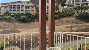 Een balkon met uitzicht op een woongebied, inclusief meer verdiepingen tellende gebouwen en een aangelegde tuin.