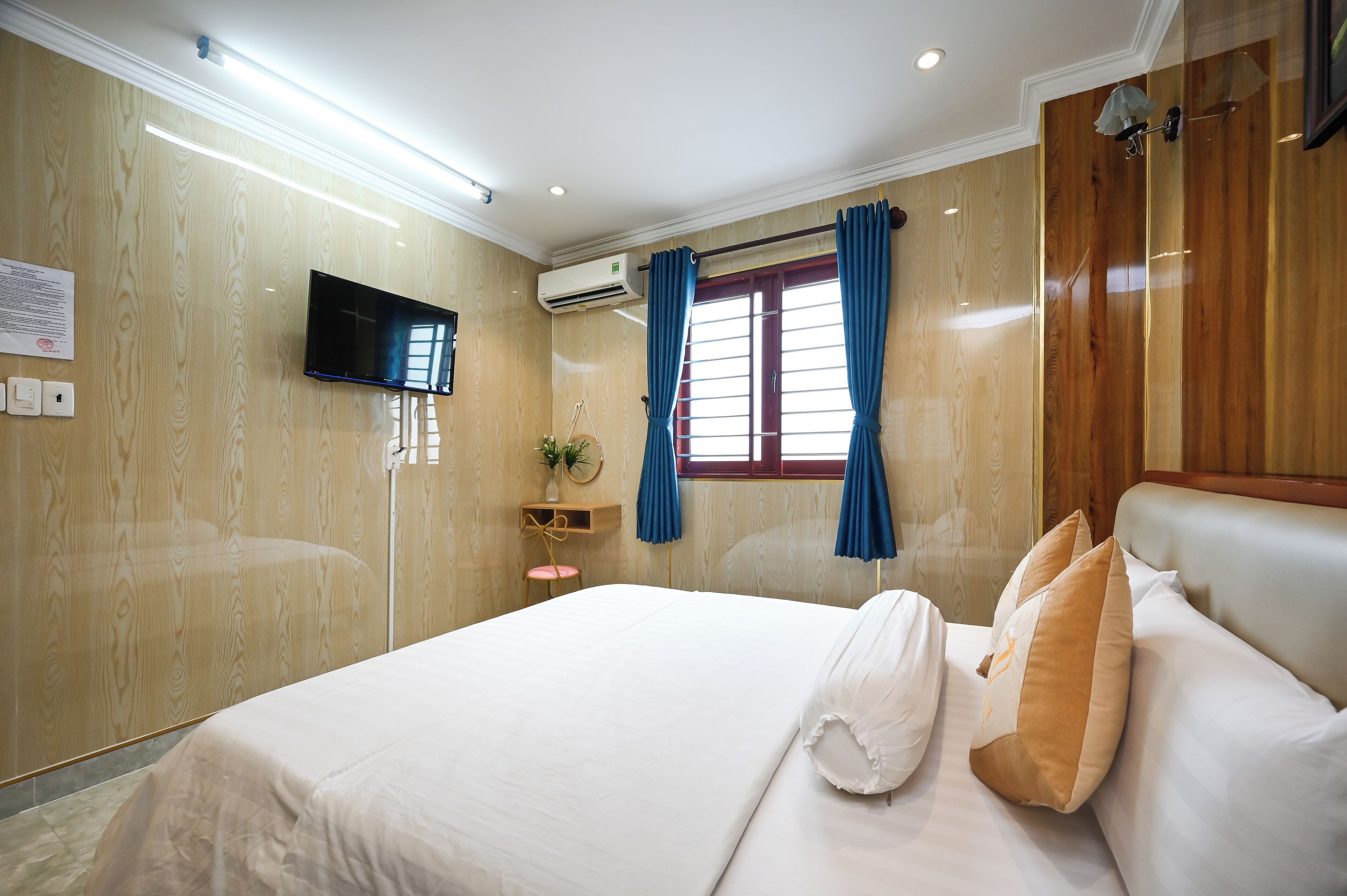 Une chambre d’hôtel équipée d’un lit, d’une télévision, d’un climatiseur et d’une fenêtre avec des rideaux.