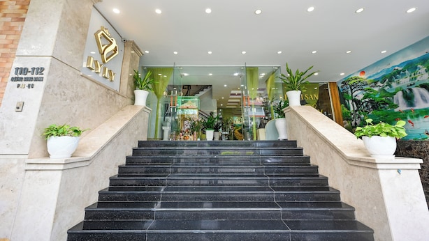 Een hotelentree met een marmeren trap, een receptiebalie en een muurschildering van een waterval.