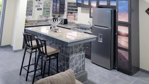 Una cucina moderna con isola centrale, sgabelli da bar, frigorifero e ventilatore a soffitto.
