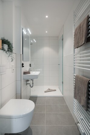 Un baño moderno con inodoro, lavamanos y ducha.