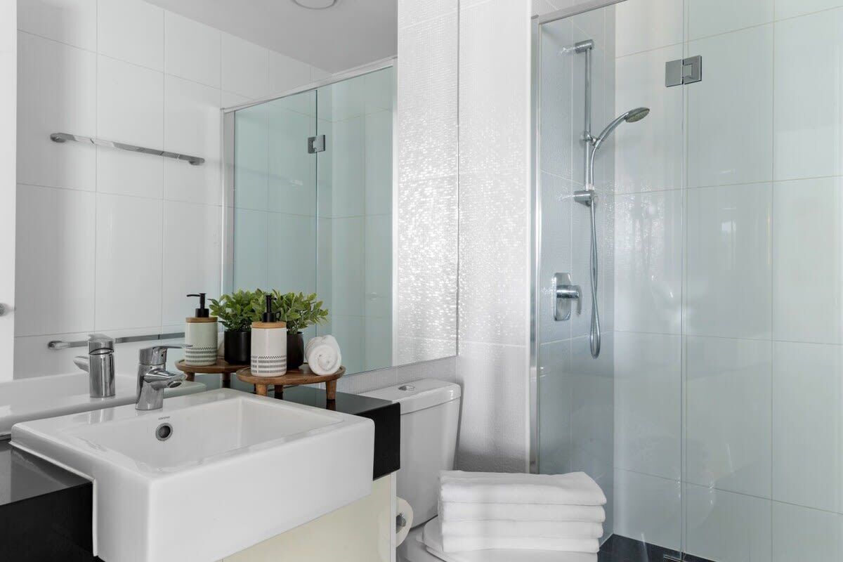 A modern bathroom with a large sink, mirror, toilet, and glass shower enclosure.